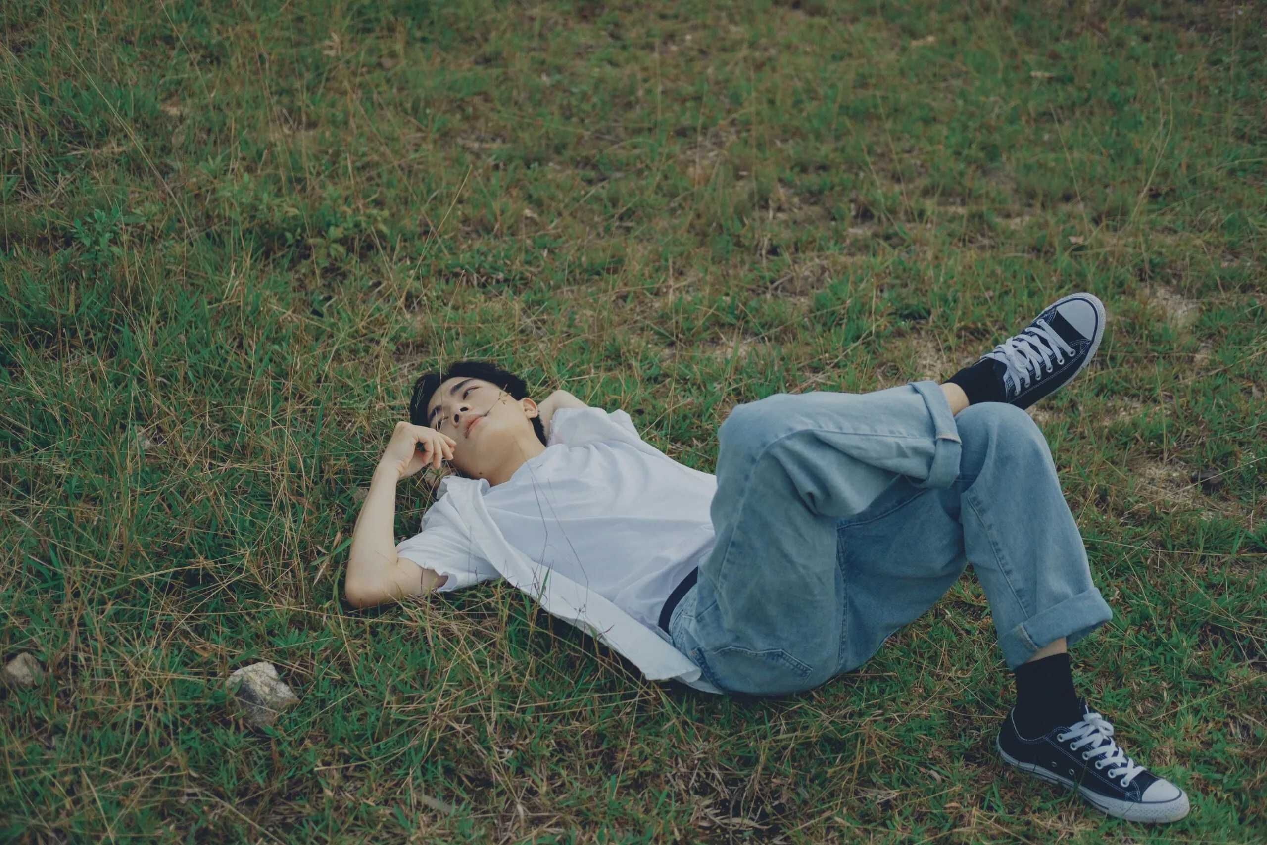 Man lying in tall grass representing mindfulness and present-moment awareness in pornography addiction recovery