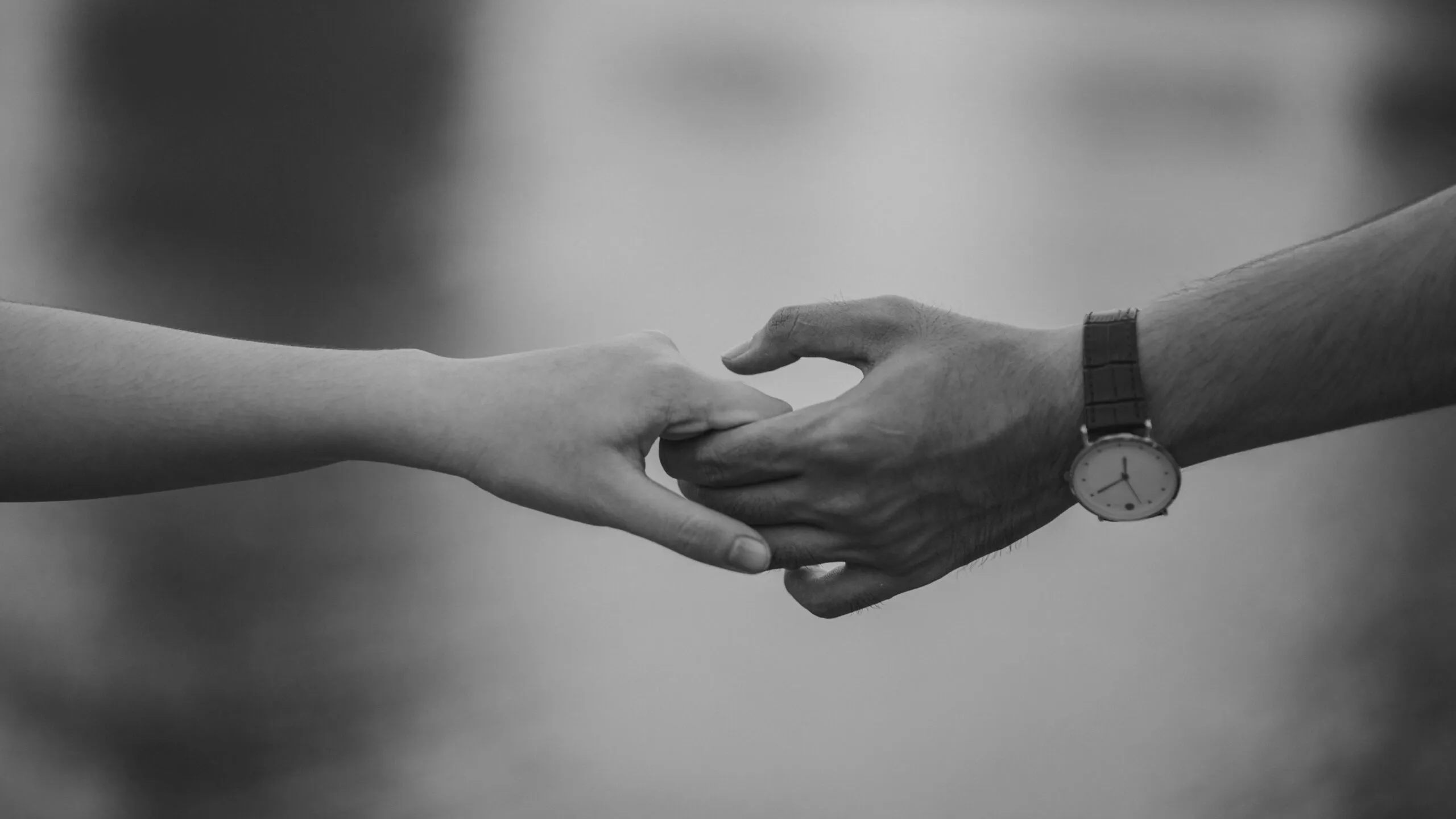 Two hands holding together in black and white representing love, connection, and the process of rebuilding trust after infidelity