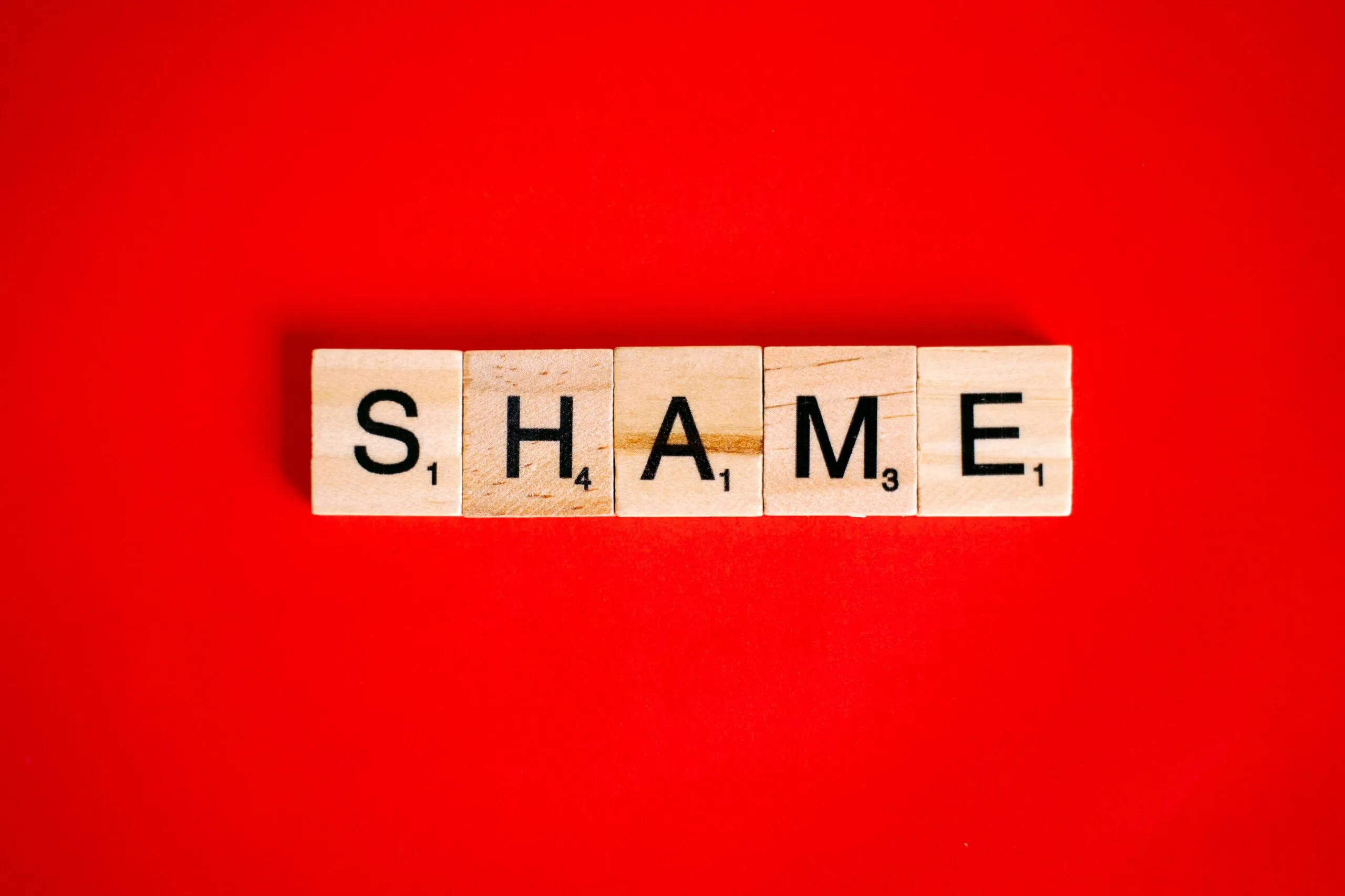 Scrabble tiles spelling the word SHAME representing the concept of shame in therapy and mental health recovery