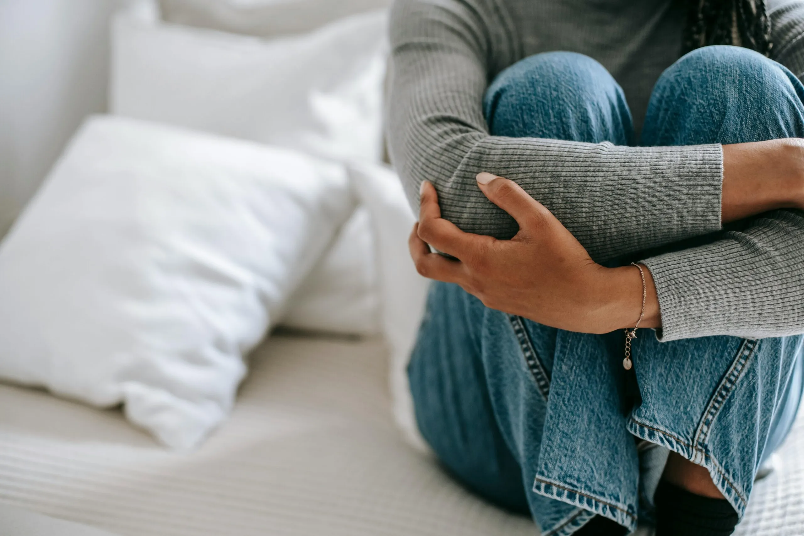 Woman sitting alone on bed representing the weight of negative self-talk and shame in recovery