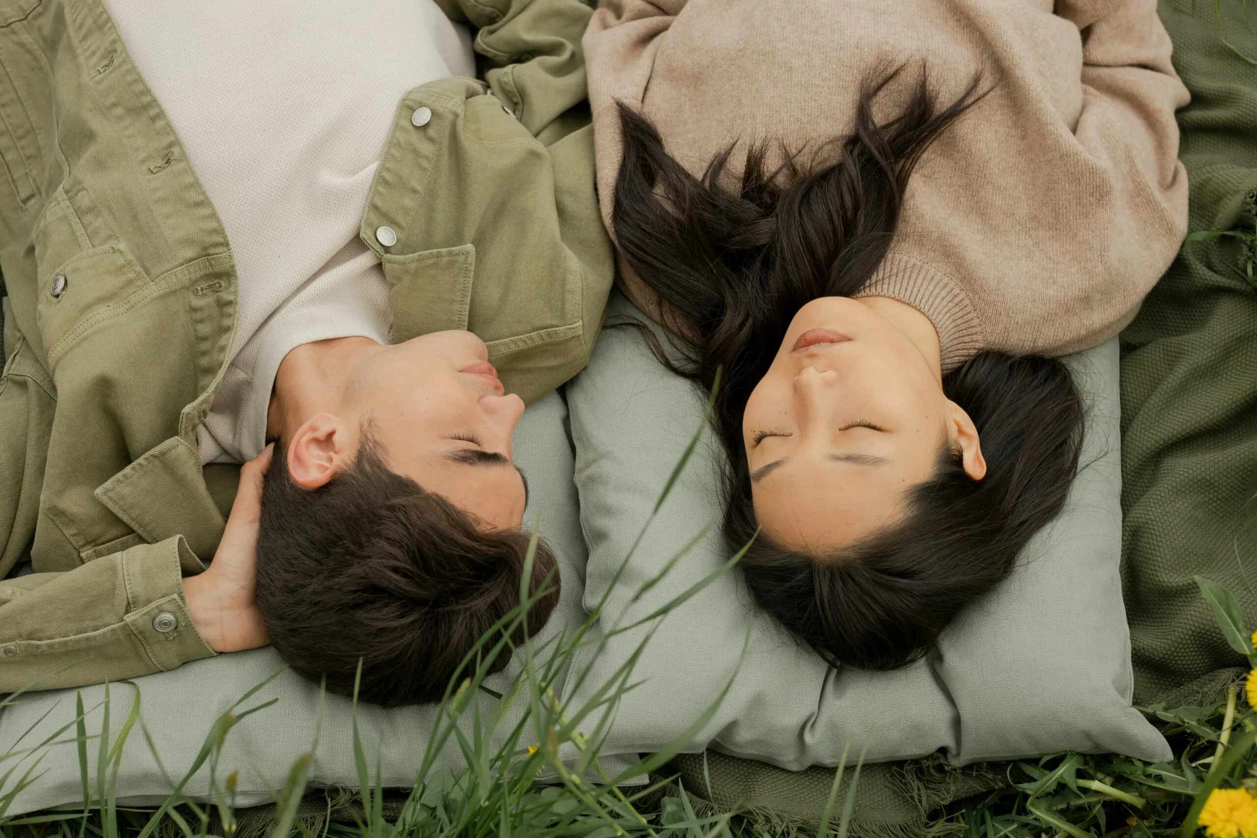 Couple lying peacefully together on grass representing secure attachment and emotional connection in relationships