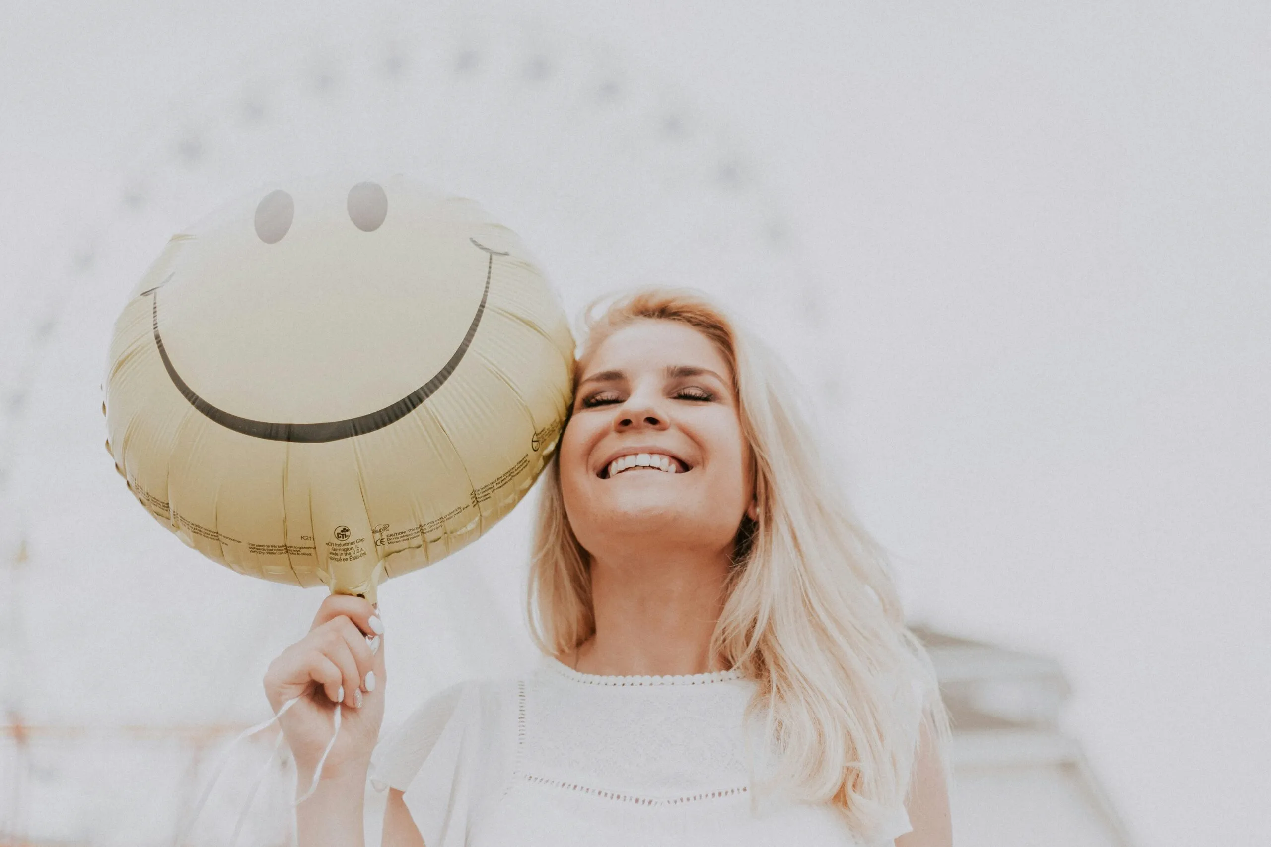 Woman holding a smiley balloon representing hope and positive mindset shift in mental health recovery