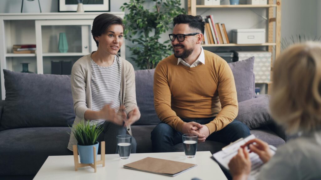 A couple discussing with a therapist during a counseling session indoors.