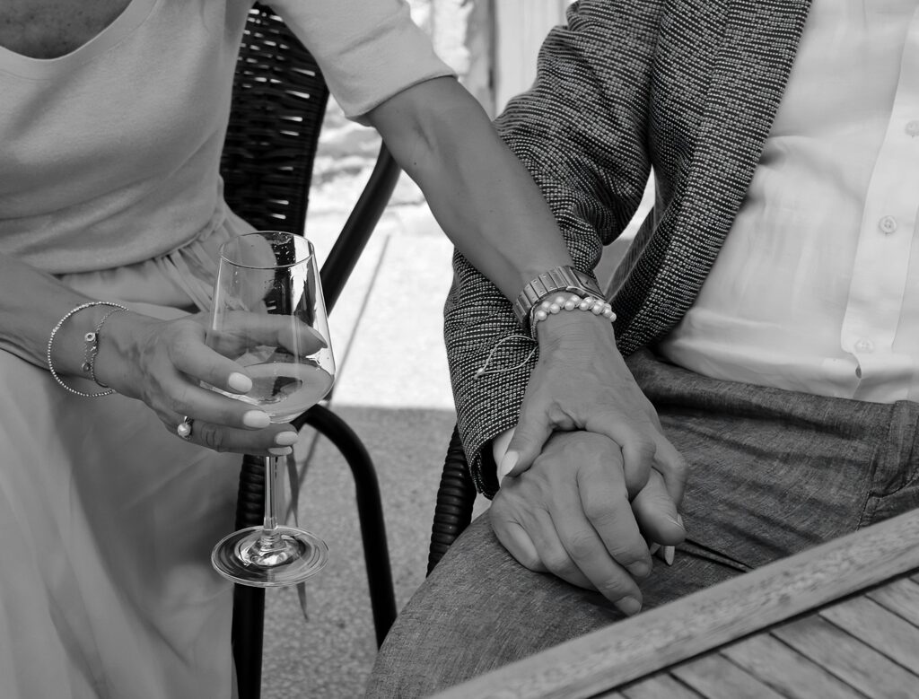 Close-up of a couple sharing an intimate moment, holding hands with a wine glass.