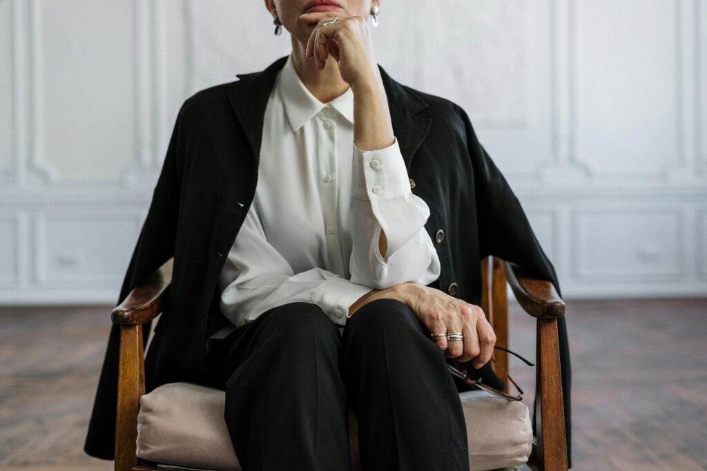 Confident woman sitting in thought, symbolizing strength and intelligence in a modern office.