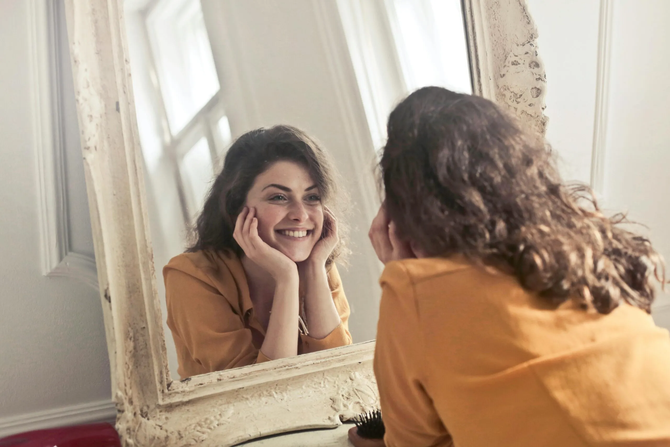 Woman smiling at her reflection representing internal validation and self-worth in therapy