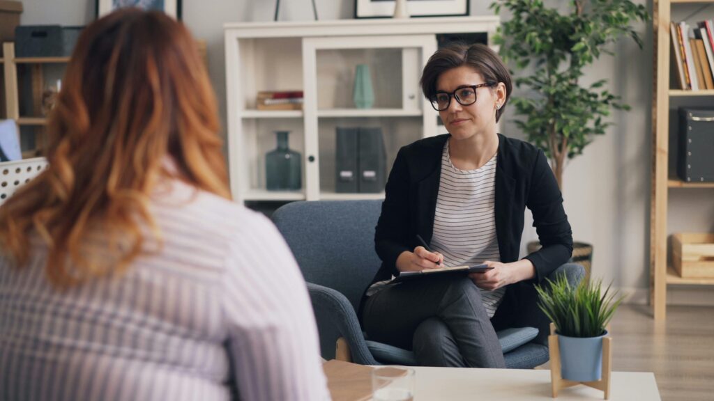 A therapist and patient having a counseling session in a modern office sitting area.