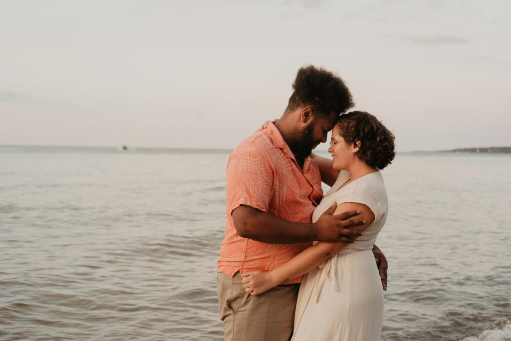 A loving couple embraces on the beach at sunset, showcasing warmth and romance.