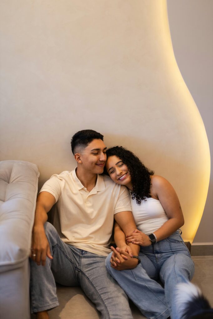 Happy couple sitting together indoors, symbolizing love and contentment.