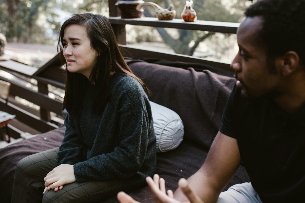 A man and woman having an emotional discussion on an outdoor bench.