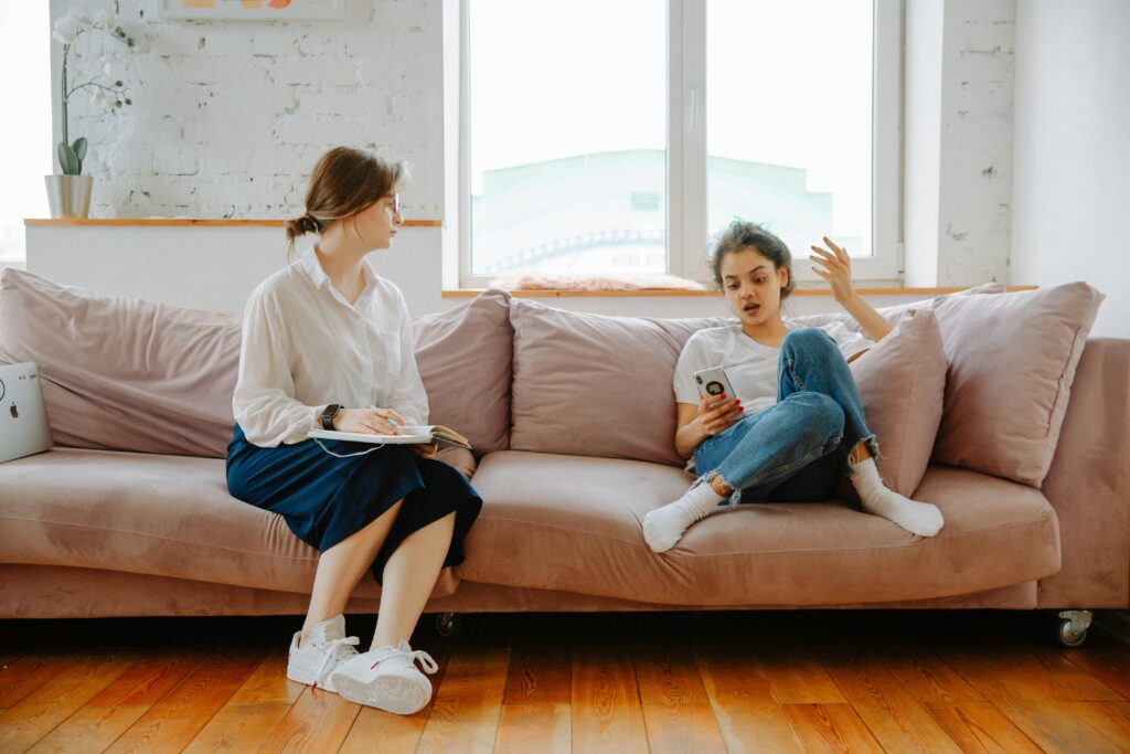 A therapist and a teenager engage in a counseling session on a comfortable sofa.