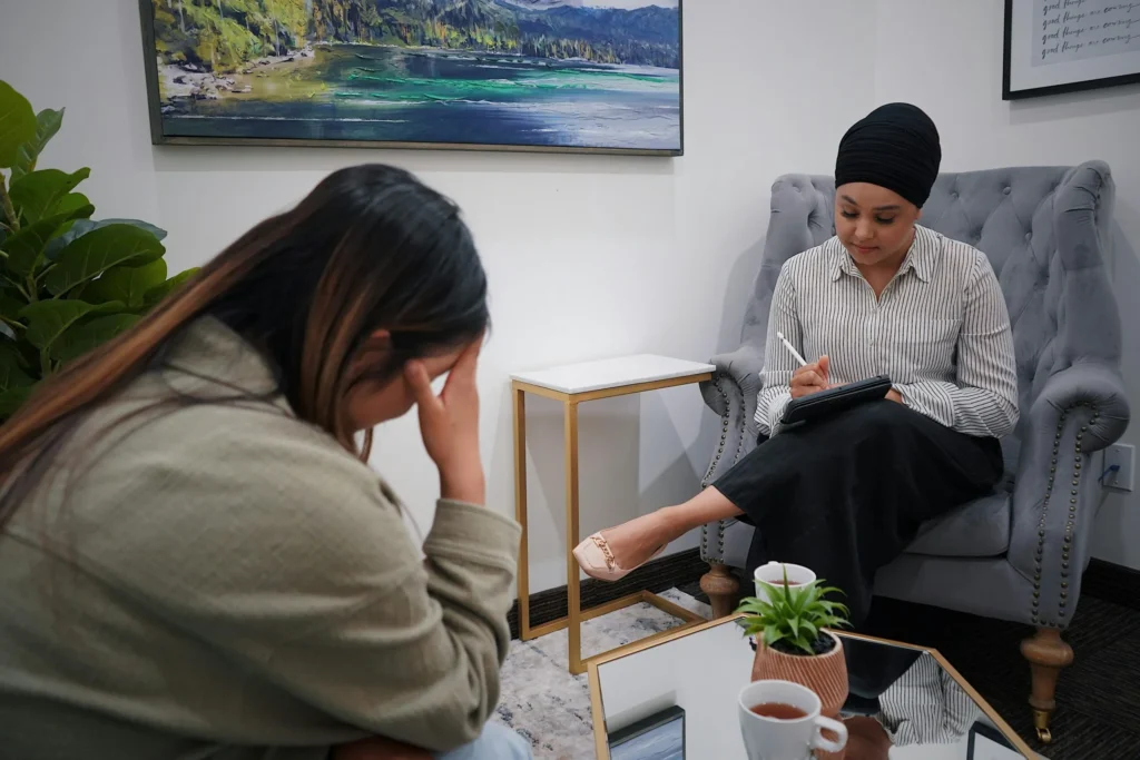 Woman sitting with therapist, holding head in frustration while discussing compulsive pornography use