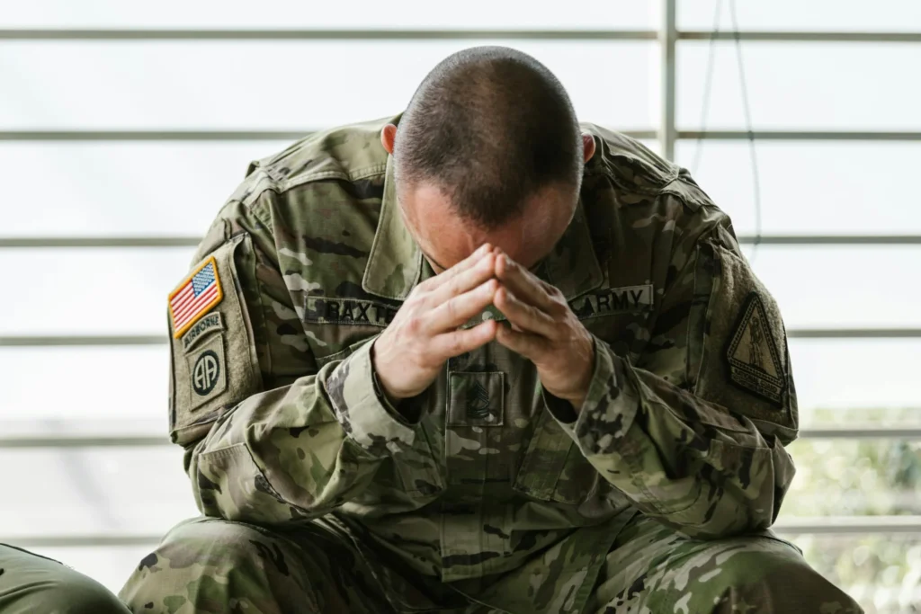 Soldier sitting indoors appearing stressed and overwhelmed — PTSD and trauma therapy Utah